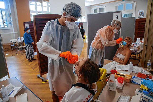Mitarbeitern des Gesundheitswesens nehmen in Paris bei zwei Frauen Nasenabstriche für einen Covid-19-Test.