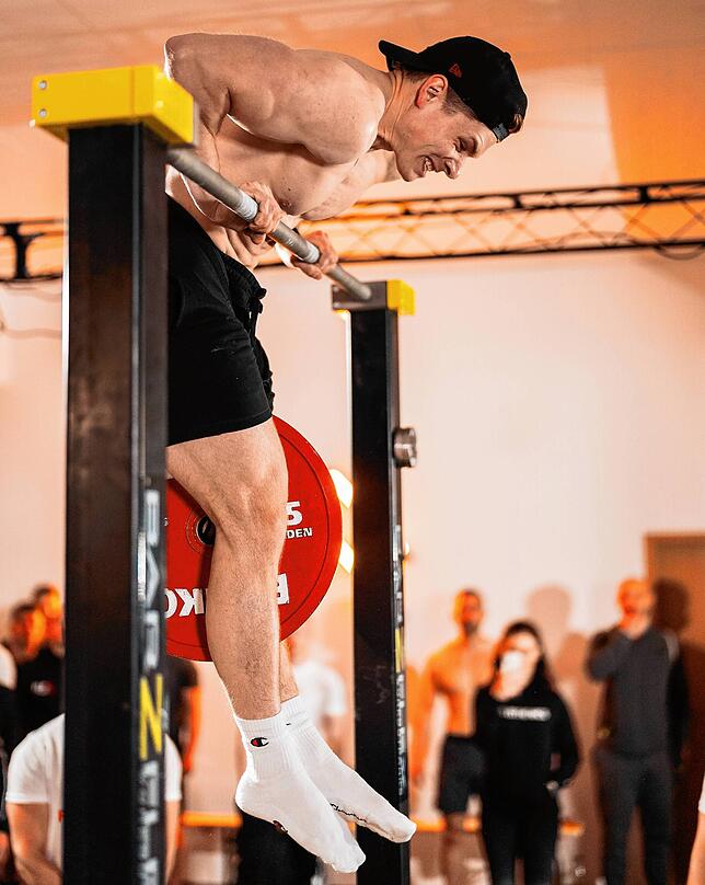 Calisthenics-Athlet Peter Buck beim Muscle-up mit 25 Kilogramm. Bild: Desicatedsports Media