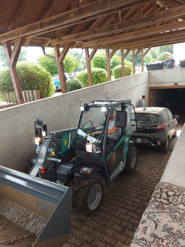 Helfer ziehen ein mit Schlamm verschmiertes Auto aus der Tiefgarage.