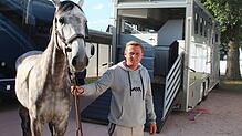 Niklas Krieg führt einen Schimmel aus dem Transporter in den Stall auf dem Reitturnier.