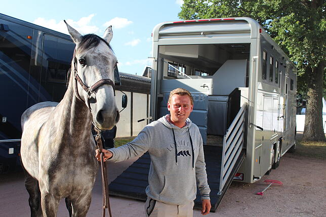 Niklas Krieg führt einen Schimmel aus dem Transporter in den Stall auf dem Reitturnier.
