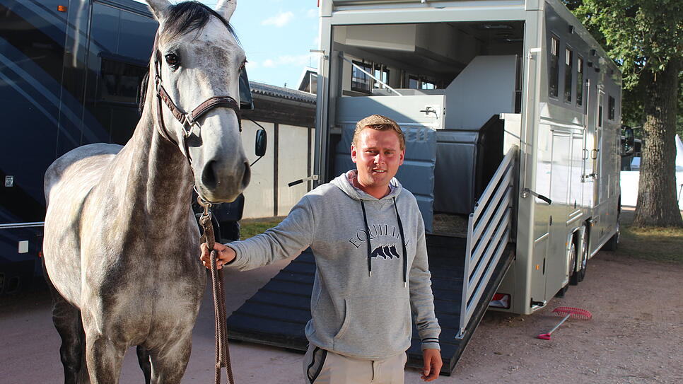 Niklas Krieg führt einen Schimmel aus dem Transporter in den Stall auf dem Reitturnier.