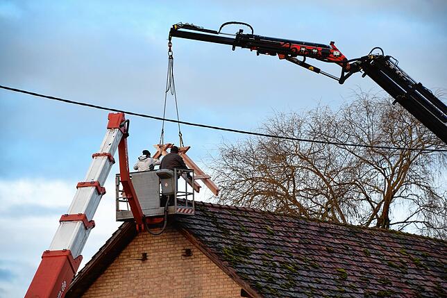 Der Dachreiter für das neue Storchennest kommt per Kran-Arm auf das Dach der Scheune auf dem Brauerei-Areal.