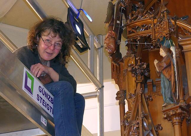 Sabine Grimmig arbeitet von einem Gerüst aus an der Kunstuhr.