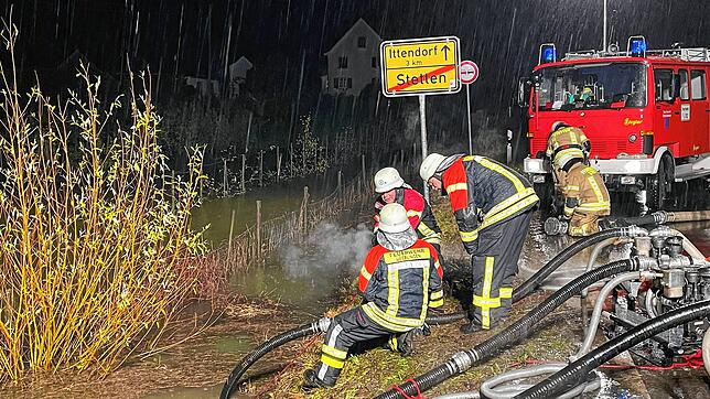Feuerwehrleute pumpen unter Hochdruck Wasser ab.