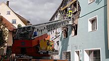 Der Feuerwehrmann schlägt den Putz samt Dämmung ab, um im dahinter liegenden Holzfachwerk nach Glutnestern zu suchen.