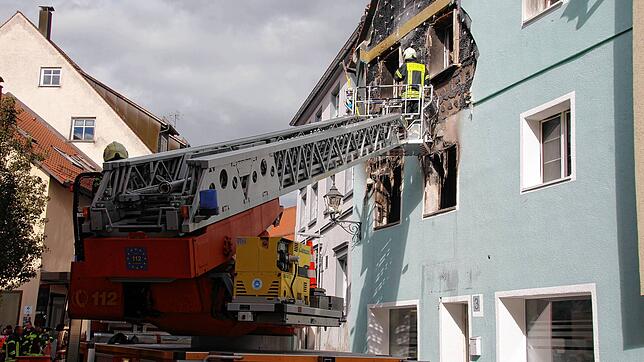 Der Feuerwehrmann schlägt den Putz samt Dämmung ab, um im dahinter liegenden Holzfachwerk nach Glutnestern zu suchen.