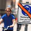 Die Masken-Regel gilt in vielen Bereichen nicht mehr: Ein mit orangenem Klebeband durchgestrichenes Hinweisschicht zur Maskenpflicht ...