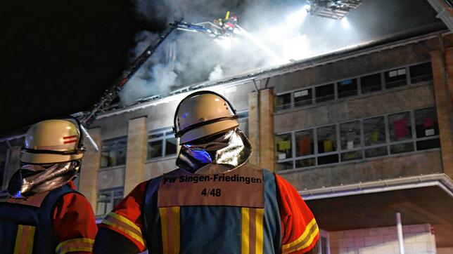 Zwei Feuerwehrmänner beobachten die Löscharbeiten an der Robert-Gerwig-Schule. Dort ist in der Nacht von Montag auf Dienstag ein Feuer ...