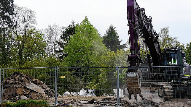 Der Abrissbagger mit seinen großen Zähnen gräbt sich durch den Boden auf dem Baugrundstück, auf dem bald ein elfgeschossiges Hochhaus ...