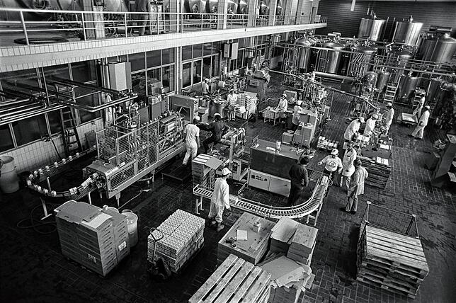 Blick in die Produktionshalle im alten Milchwerk in den 1970er Jahren. Auf der linken Seite sind gut die weißen Fliesen, die Säulen und ...