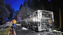 Feuerwehrleute stehen neben einem ausgebrannten Bus. Der Linienbus ist bei Mittelbiberach in Brand geraten.