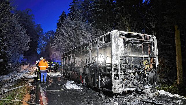 Feuerwehrleute stehen neben einem ausgebrannten Bus. Der Linienbus ist bei Mittelbiberach in Brand geraten.