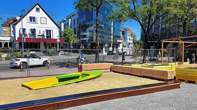 Im Sandkasten befindet sich ein Boot in der Mitte, ringsum gibt es Sitzgelegenheiten auf massiven Holzbalken.