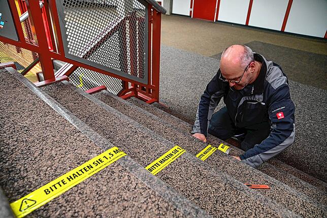Martin Kienzler erneuert die Linien auf den Schultreppen, die die Schüler auf Einhaltung der Abstandsregeln hinweisen.