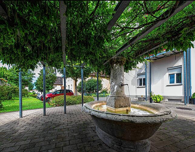 Ein schattiges Plätzchen mit einem kühlenden Brunnen wird von den Bewohnern der Seniorenwohnanlage gerne angenommen.
