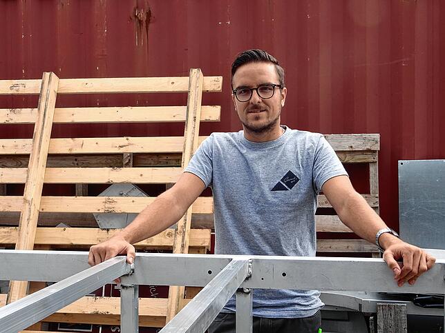 Christoph Joos vor den Teilen eines Werbeturms, den er mit seinem Team zusammenbaut.
