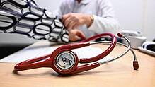 Ein Arzt misst in einer Bereitschaftspraxis bei einer Patientin den Blutdruck (Symbolbild, gestellte Szene). Im Vordergrund liegt ein ...