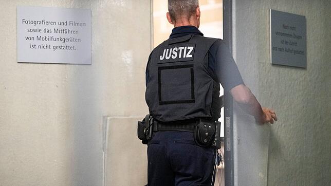Ein Justizbeamter schließt beim Auftakt im Prozess gegen drei mutmaßliche IS-Sympathisanten die Tür zu einem Saal des Landgerichts Mannheim.