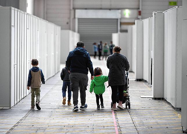 Eine Flüchtlingsfamilie geht durch die zu einer Massenunterkunft umfunktionierten Messehalle in Frankfurt.