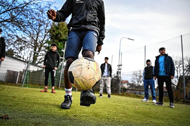 Der jugendliche Flüchtling Assani (vorn) aus Burundi spielt auf einem Bolzplatz in Langenargen Fußball mit anderen geflüchteten ...