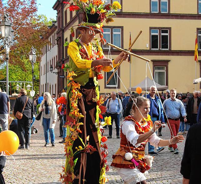 Duo Minuusch: Bunt dekorierter Stelzenläufer mit Marionette.