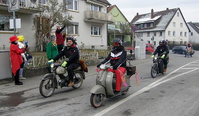 Sie werden von kostümierten Zuschauern am Straßenrand beklatscht und fotografiert.