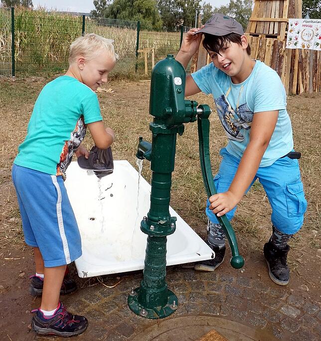 Erfrischung: An heißen Tagen ist das kühle Wasser aus dieser Pumpe eine willkommene Abkühlung für die Kinder, hier Maxim (links) und ...