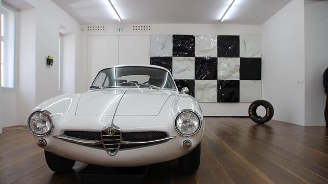Das schlägt das Herz höher: ein Alfa Romeo Guilia Sprint-Speciale. Im Hintergrund "Pole Position", das aus Motorhaben besteht.