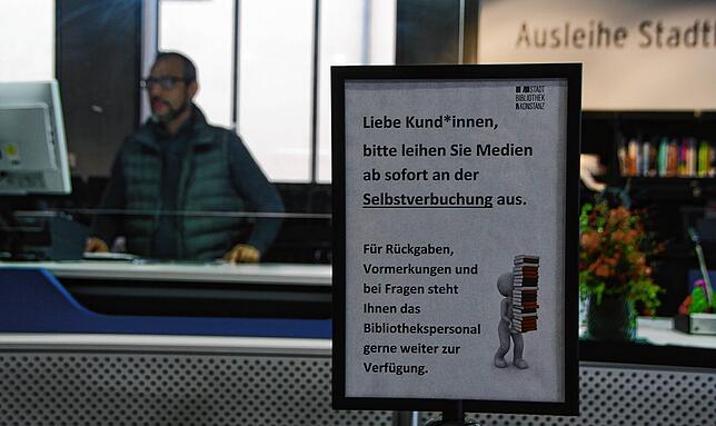 Ein Schild informiert an den Schaltern der Konstanzer Stadtbibliothek, dass die Besucher ihre Medien an Terminals nun selbst zur ...