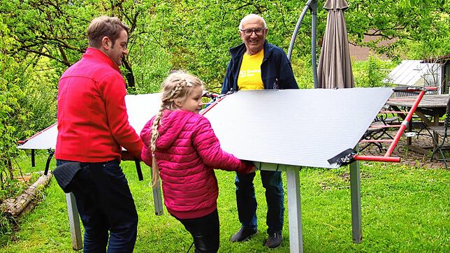 Der Sonne entgegen: Florian Gutmann und seine Tochter Marika (vorne) drehen ein mobiles Balkonkraftwerk für eine bessere Stromausbeute ...