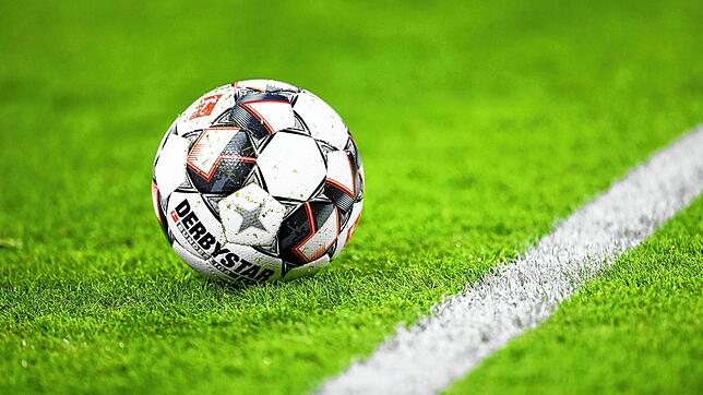 Ein Fußball liegt auf dem Rasen (Symbolbild). Nach einer Schlägerei auf einem Jugend-Fußballturnier ist ein 15-Jähriger für hirntot ...