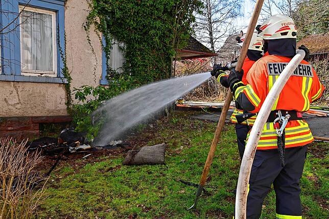Das verkohlte Inventar wird vor dem Haus abgelöscht.