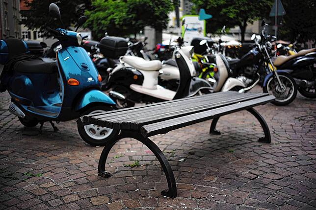 Fischmarkt kostenlos: Hier lädt eine Sitzbank zur Pause mit Blick auf geparkte Motorroller ein.