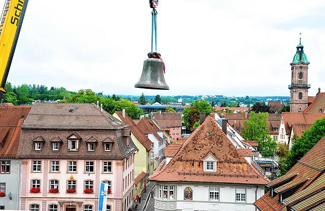 Was für ein Anblick: Die tonnenschwere Glocke schwebt über dem Pfarrhaus, im Hintergrund ist der Turm der Benediktinerkirche zu sehen.