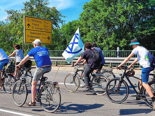 Ein Teilnehmer hat die Fahne der Aktivistengruppe Extinction Rebellion am Gepäckträger gehisst.