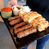 Cevapcici mit Fladenbrot, Zwiebeln, Ajvar und dem Balkan-Käse Kaschkawal, ein strohfarbener Filata-Käse aus Schafmilch.