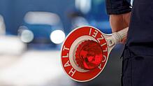 Ein Polizist hält eine Anhaltekelle in der Hand.