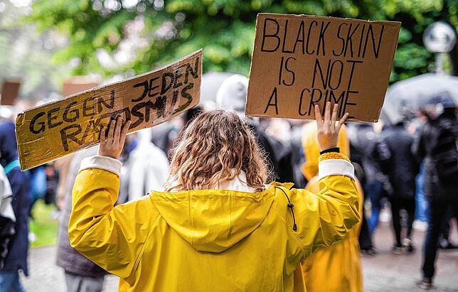 „·Gegen jeden Rassismus“ (l-r)· und „·Black skin is not a crime·“ steht auf Schildern einer Teilnehmerin ...