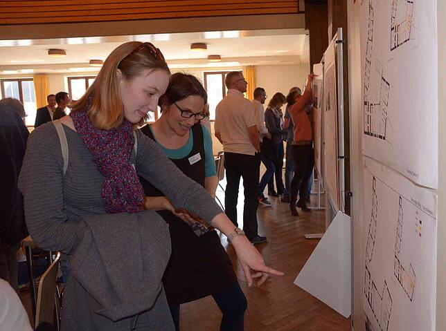 Lisa Gretscher (links) und Jule Schmid studieren die an Stellwänden in der Stadthalle ausgehängten Baupläne.