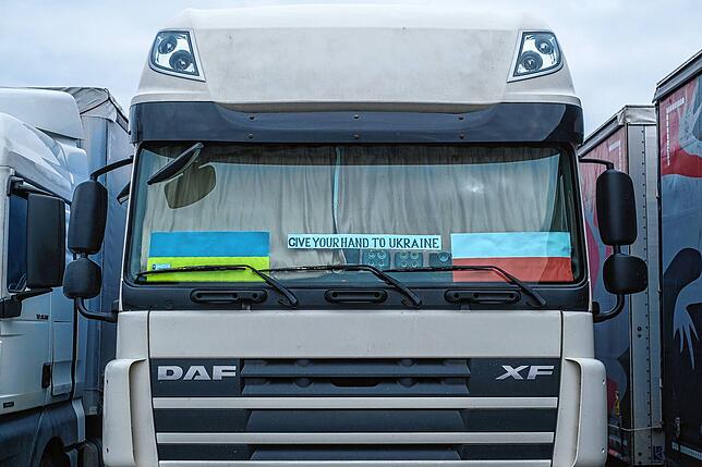 „Give your hand to Ukraine“ steht in der Windschutzscheibe eines Lastkraftwagens auf der Autobahnraststätte. Viele ...