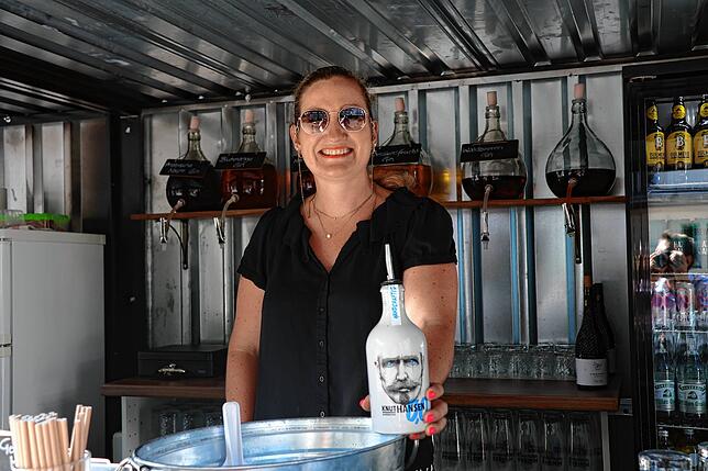 Sam Dilnot in ihrer Pop-Up-Bar auf dem Kirchplatz – in der Hand hat sie den alkoholfreien Gin, den sie anbietet.