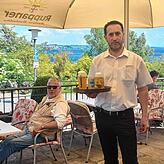 Elvir Tukic, seit vielen Jahren im Service im Hohenegg, bringt einem Gast sein Bier. Hier im Schatten mit Blick auf den See lässt es ...