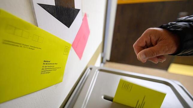 Ein Mann wirft einen Wahlbrief für die Kommunalwahl in Baden-Württemberg in eine Wahlurne.