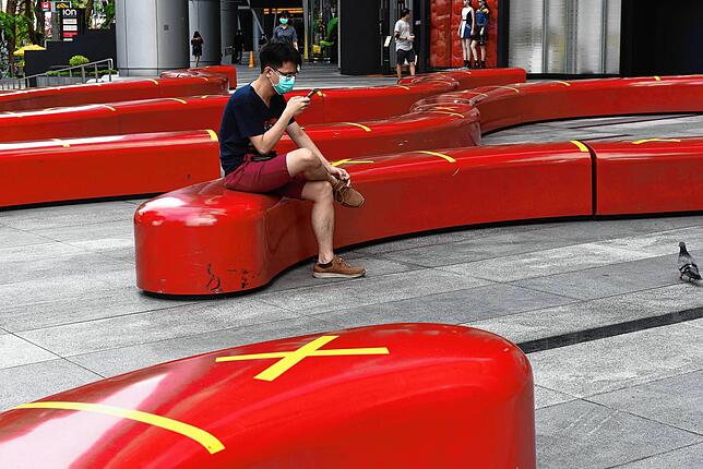 Ein Bewohner von Singapur schaut auf sein Handy. Bild: AFP