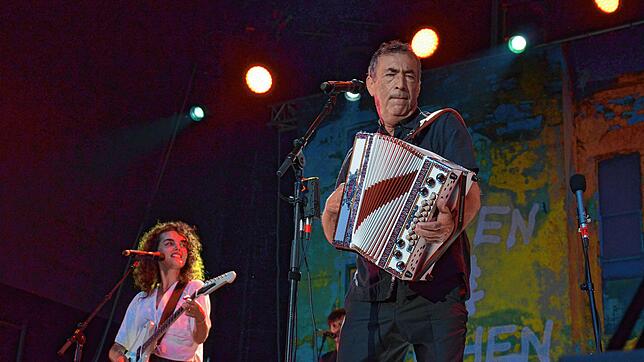 Weltmusiker Hubert von Goisern steht im Salemer Schlosspark auf der Bühne. Die Harmonika ist nur eines der Instrumente, die er spielt.