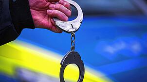 Ein Polizist hält Handschellen (Symbolbild). Handschließen sind auch bei einer Ingewahrsamnahme in Lörrach zu Einsatz gekommen.