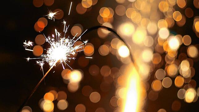 Eine große Wunderkerze brennt in der Silvesternacht vor einer gezündeten Silvesterrakete. Wegen der Corona-Pandemie gibt es dieses Jahr ...