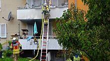 Während es in der Erdgeschosswohnung brennt, versuchen die Einsatzkräfte der Feuerwehr, die Wohnung im ersten Stock zu sichern.