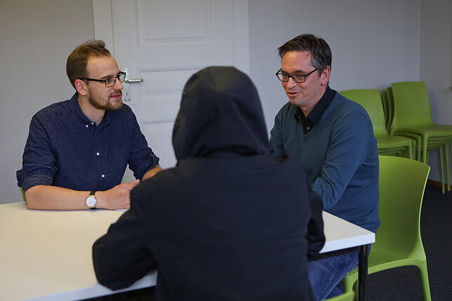 Volontär Jonas Schönfelder im Gespräch mit David Resch* und dem Psychotherapeuten Daniel Nischk (von links)